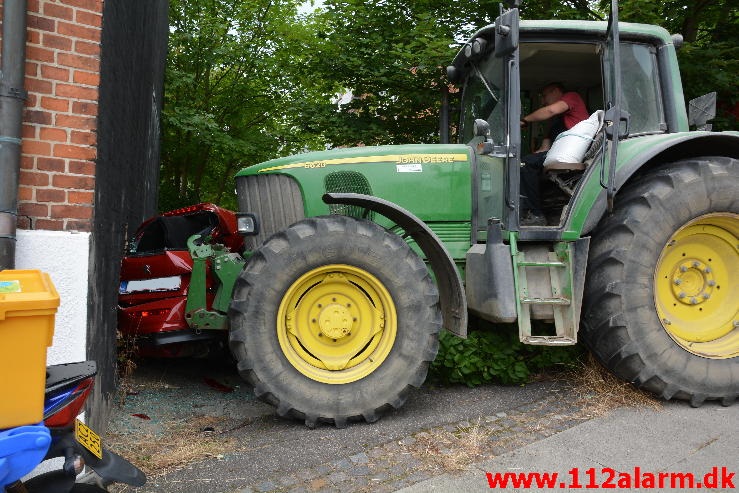 Traktor skubbet bil gennem vægen.